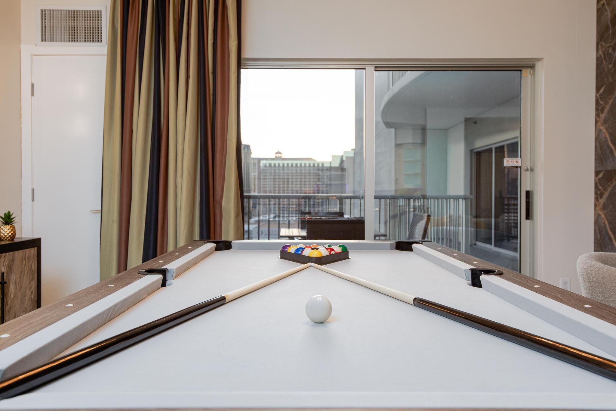 Une table de billard avec une boule blanche, un jeu de billes colorées et un porte-billes.