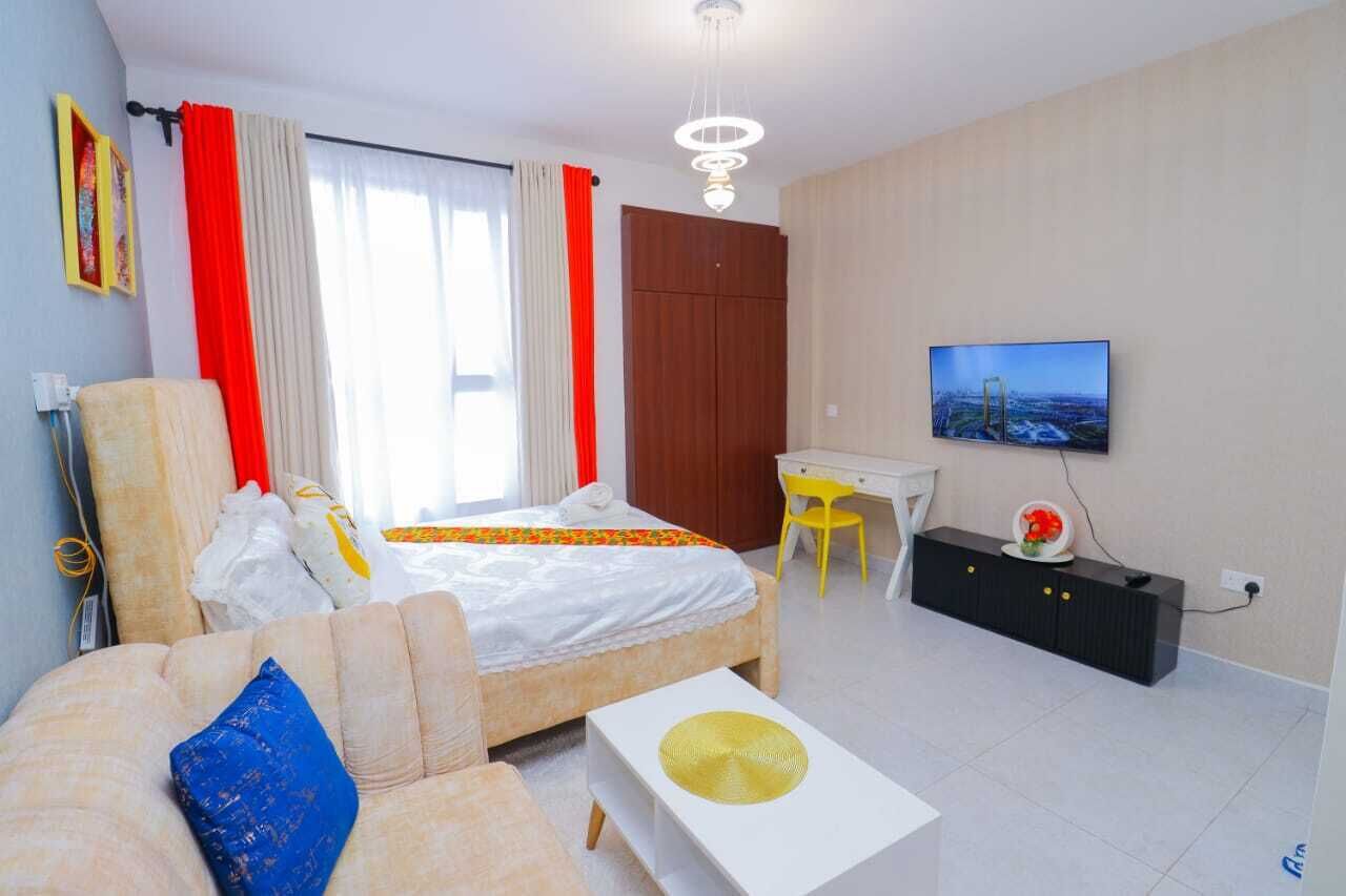 A modern hotel room with a bed, a sofa, a desk, and a television.