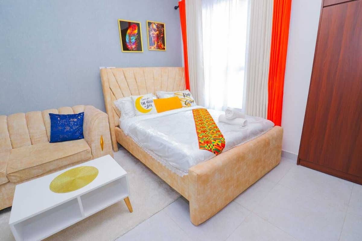 A bedroom with a bed, a sofa, and a white coffee table.