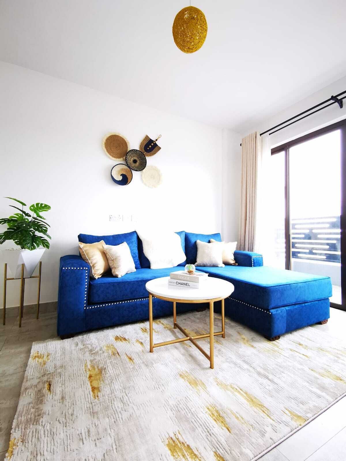 A modern living room with a blue sectional sofa, a round coffee table, and a decorative wall piece.