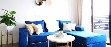 A modern living room with a blue sectional sofa, a round coffee table, and a decorative wall piece.