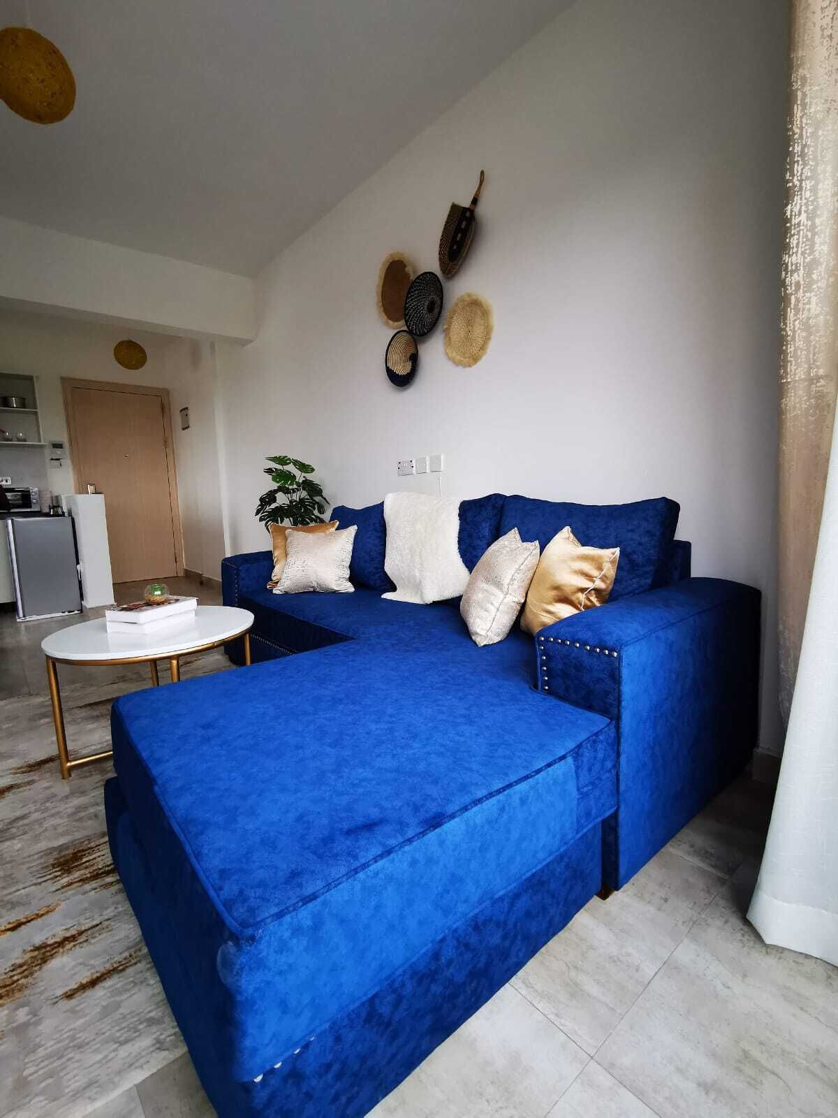 Una sala moderna con un sofá seccional azul, una mesa de centro blanca y una planta en maceta.