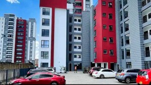A modern apartment building with multiple floors, balconies, and a parking area with cars. - Lux Suites Enkang Apartments Ngong Road (Nairobi)