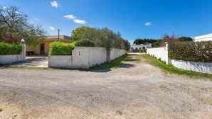 A gravel driveway leading to a building with a concrete wall and greenery on the sides. - 3847 Villetta Le Largure B by Barbarhouse (Melendugno)