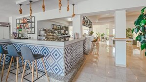 A modern bar area with a patterned bar counter, stools, and a variety of bottles and glasses. - Hotel Lliteras (Capdepera)
