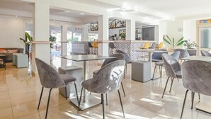A modern hotel lobby with a bar area, seating arrangements, and a view of the outdoor space. - Hotel Lliteras (Capdepera)