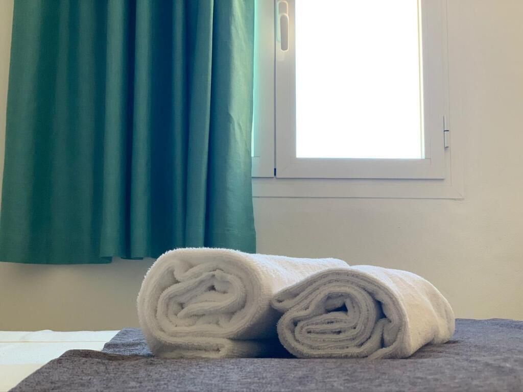 Une salle de bain avec une fenêtre, une serviette et un rideau.