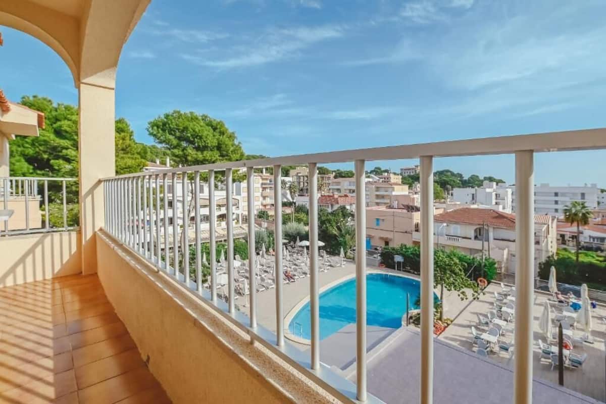A balcony with a view of a swimming pool and surrounding buildings.
