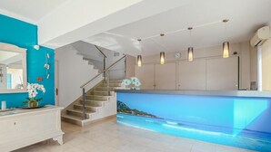 A modern kitchen with a large island, a staircase, and a view of the ocean through a large window. - Hotel Lliteras (Capdepera)