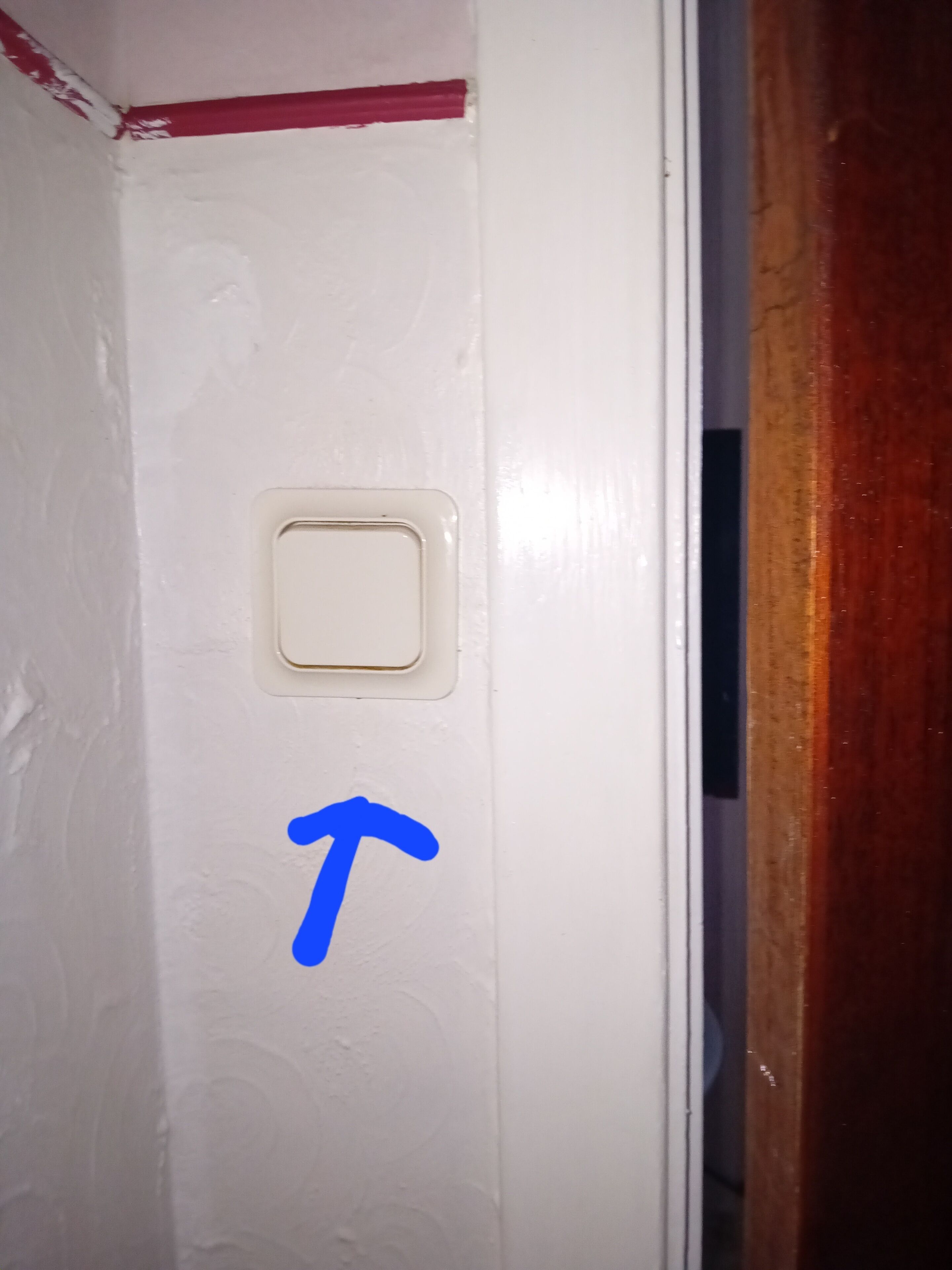 Une porte blanche avec une petite grille carrée et une flèche bleue pointant vers le bas.