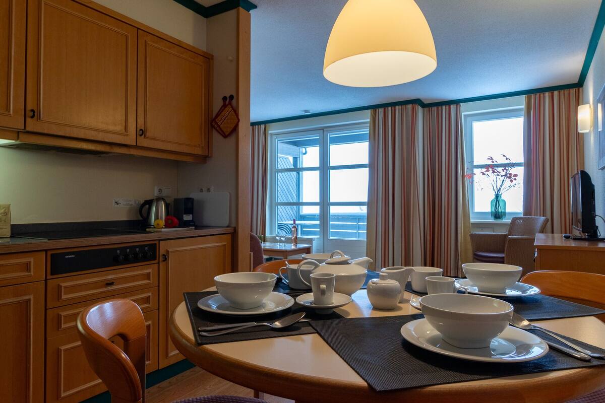 A kitchen with wooden cabinets, a Siemens dishwasher, and a dining area with a table set for four.