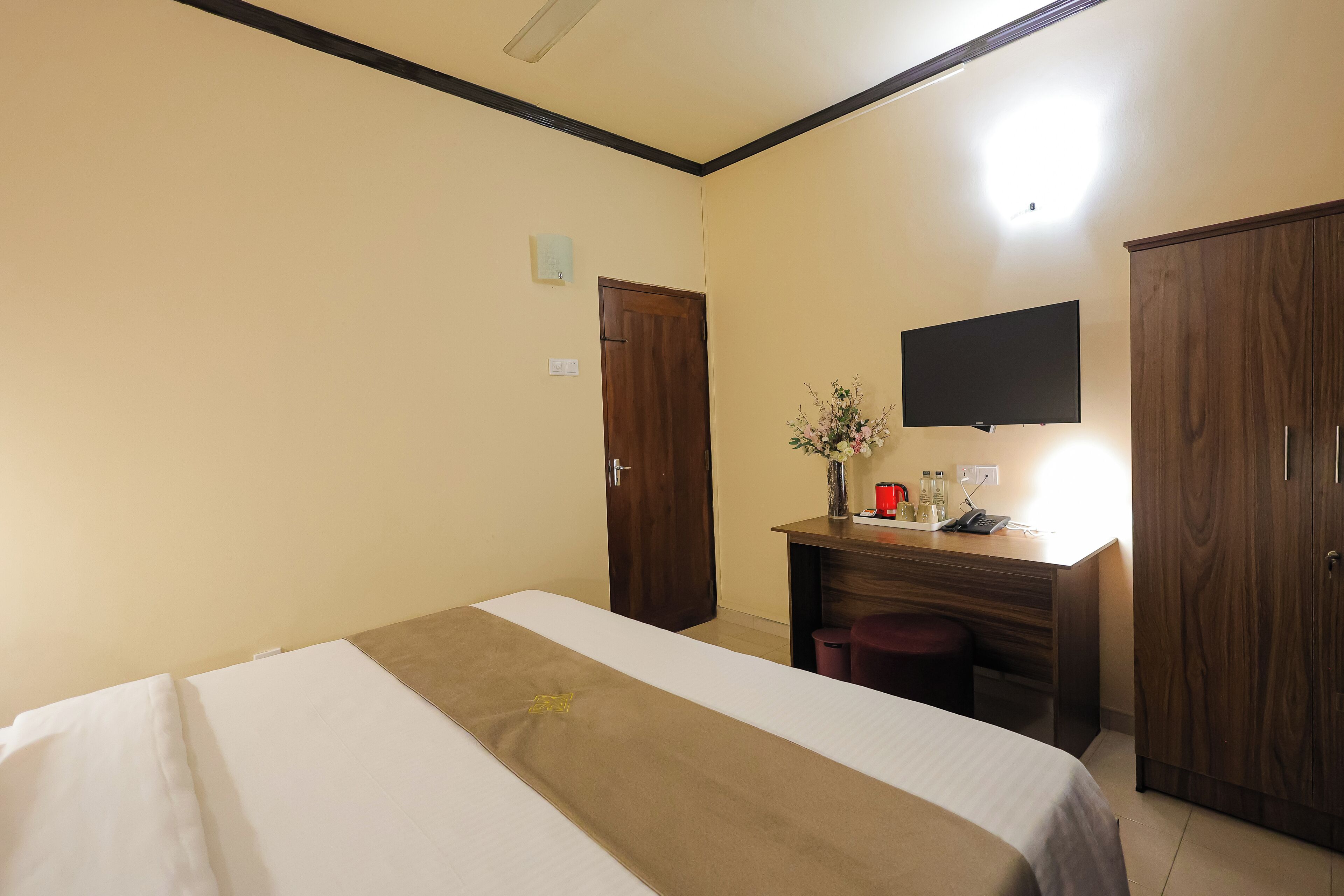 Una habitación de hotel con una cama, un escritorio, un televisor y un armario.