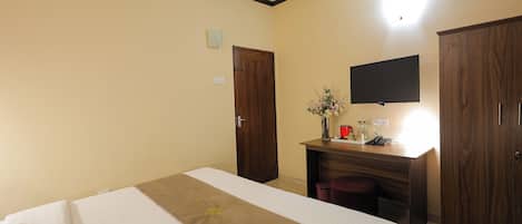 Una habitación de hotel con una cama, un escritorio, un televisor y un armario.
