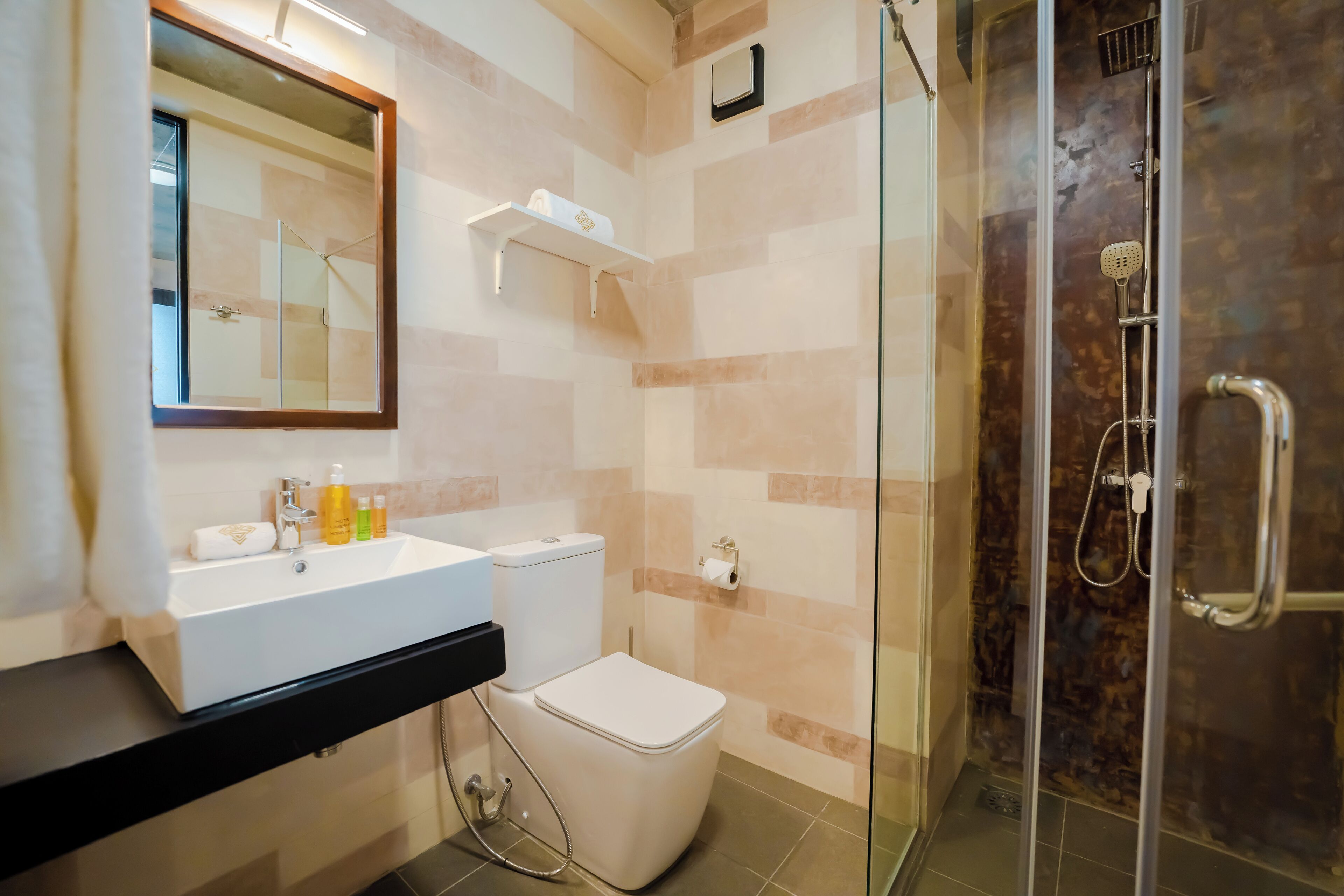 A modern bathroom with a glass-enclosed shower, a white sink, and a toilet.