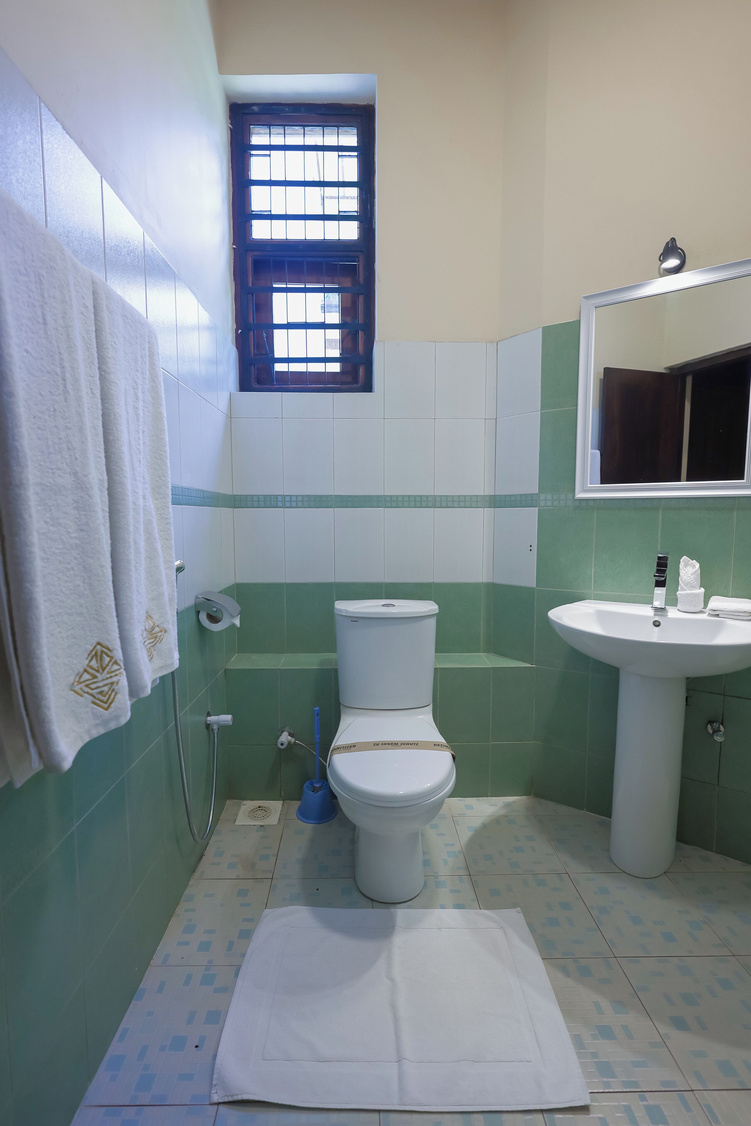 A bathroom with a toilet, sink, and a window.