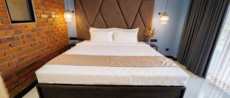 A modern hotel room with a brick wall, a large bed with a headboard, and two pendant lights.