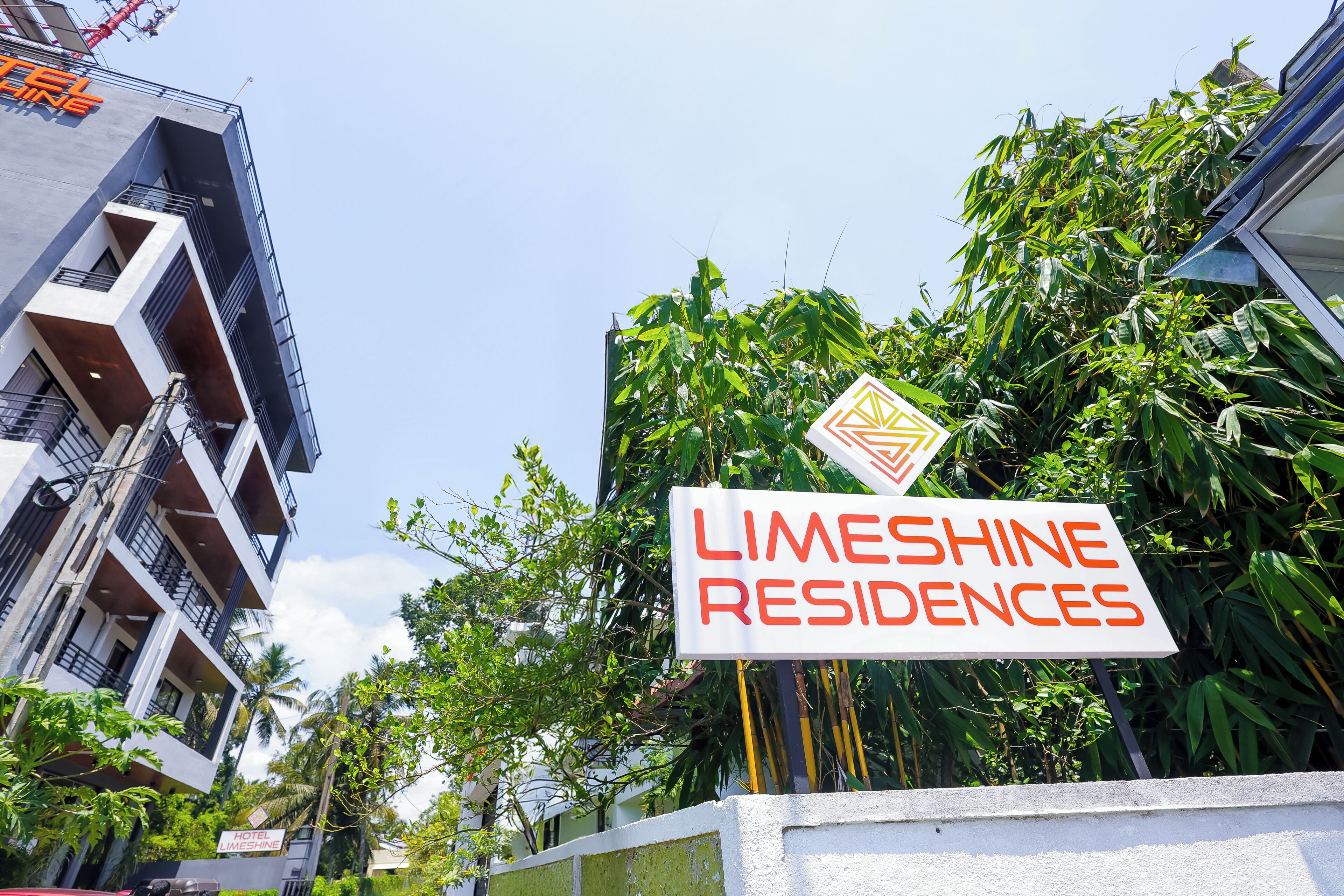 A sign for Limeshine Residences with a modern building in the background.