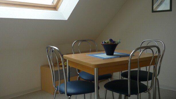 A dining area with a wooden table, four chairs, a potted plant, and a skylight. - Ferienwohnung an der Saline, Nr. 3 (Rheine)