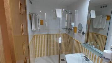 Un baño con ducha, lavamanos y espejo.