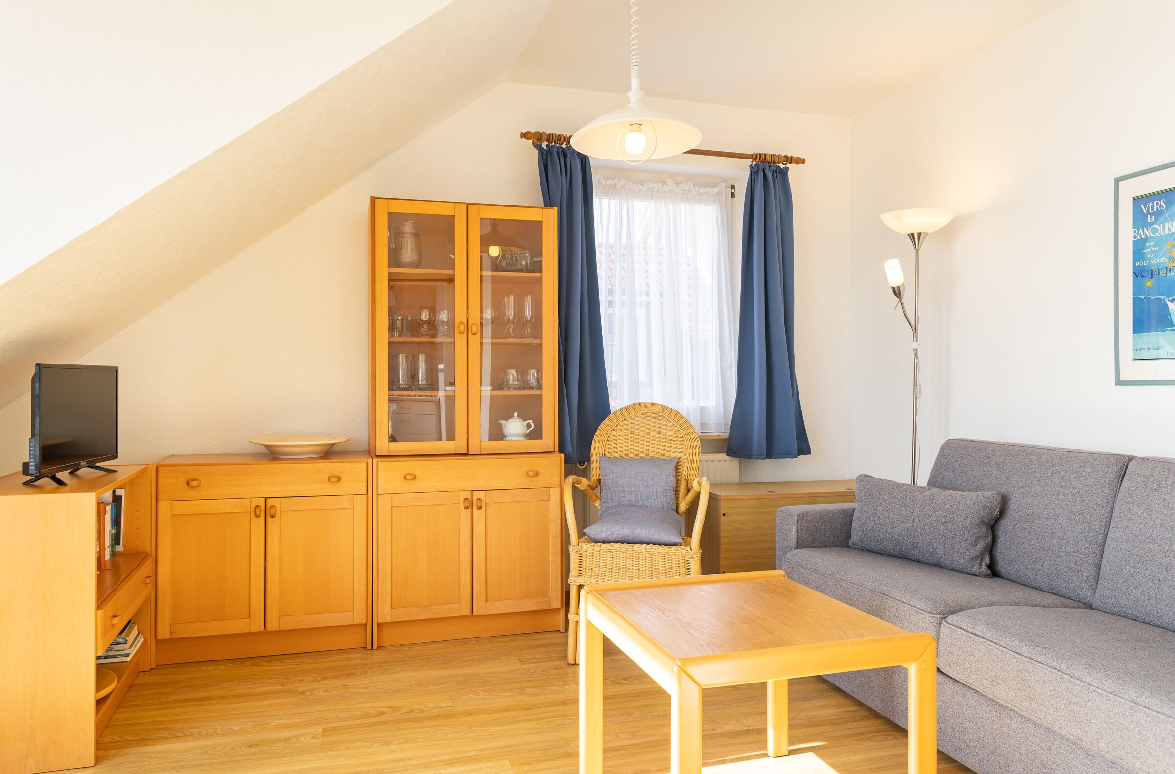 Un salon chaleureux avec un canapé, une table en bois, un fauteuil en osier et un meuble avec des portes en verre.