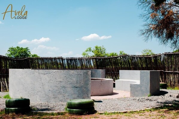 An outdoor seating area with concrete planters and tires, surrounded by a bamboo fence.