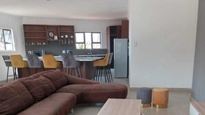 A modern living room with a sectional sofa, a wooden coffee table, and a cowhide rug. - Bikos Villa (Magaliesberg)