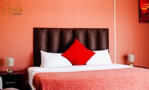 A hotel room with a bed, a red pillow, and two bedside lamps.