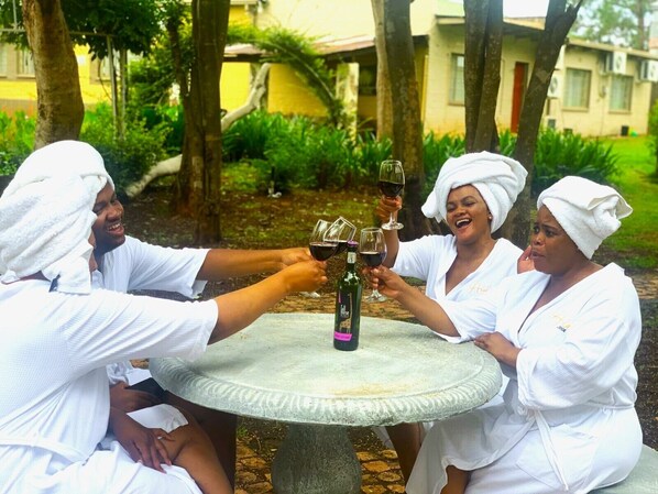 Cuatro personas brindando con copas de vino alrededor de una mesa de piedra en un jardín.