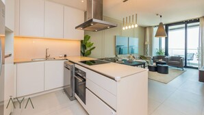 A modern kitchen with white cabinetry, a stainless steel range hood, and a central island. - Aya - Beachfront Bliss 2BR Haven at The Beach Residences (Dubai)