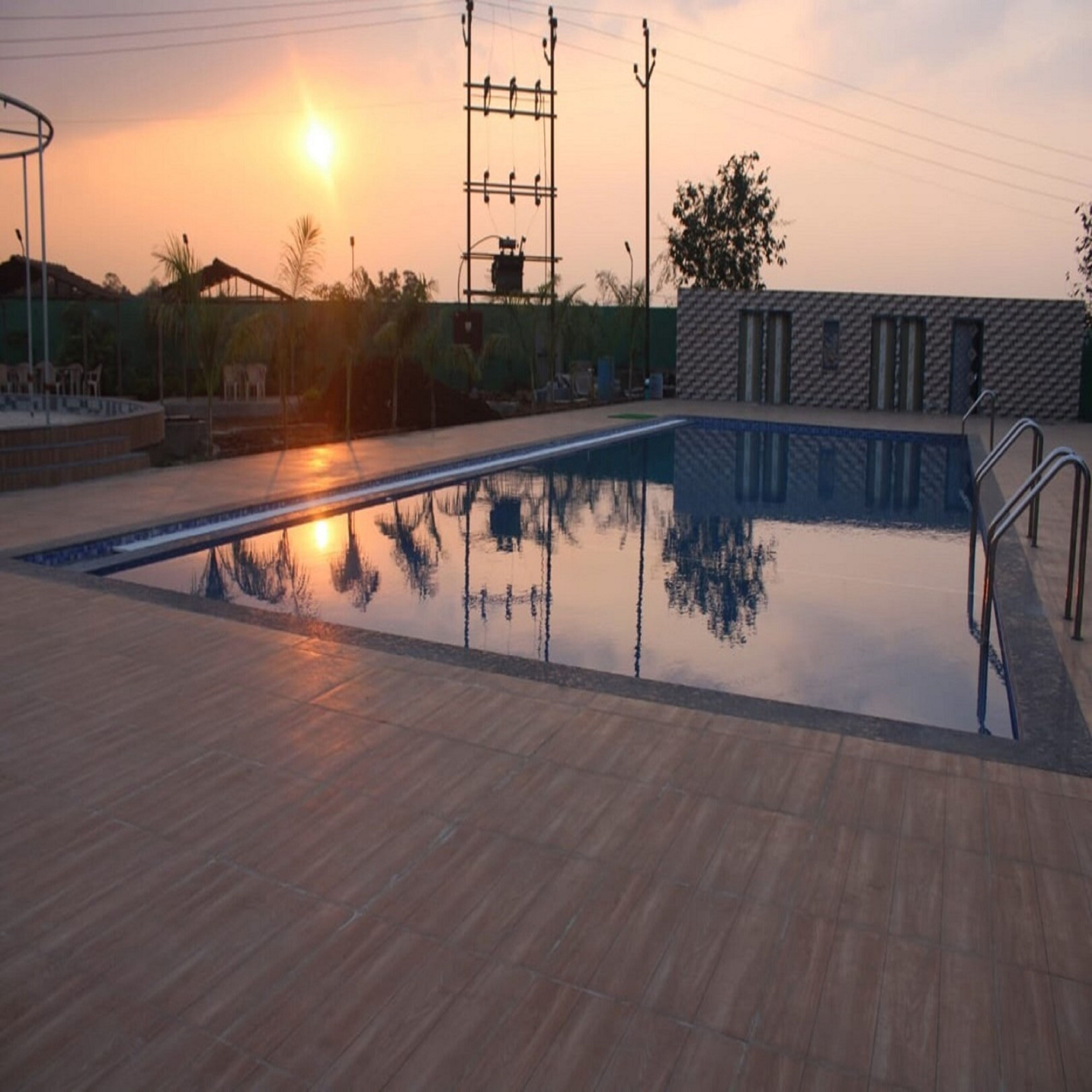 A swimming pool with a clear reflection of the sunset and surrounding buildings.