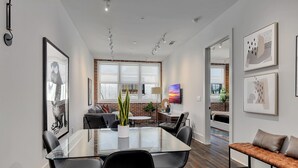 A modern interior with a glass-top dining table, black chairs, a leather bench, and artwork on the walls. - Loft Style Spacious Lux Apt 202, sleeps 6 (Atlanta)