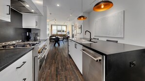 A modern kitchen with a central island, stainless steel appliances, and a wooden floor. - Loft Style Spacious Lux Apt 202, sleeps 6 (Atlanta)