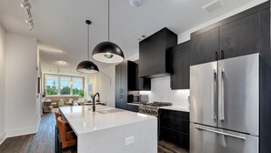A modern kitchen with a central island, stainless steel appliances, and dark cabinetry. - Loft Style Spacious Lux Apt 203, sleeps 6 (Atlanta)