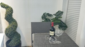 A small outdoor seating area with a wicker table and chairs, a potted plant, and a bottle of wine. - Pop Art Luxury Room Marylebone  (London)