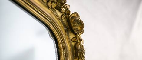 Primer plano de un espejo con marco dorado y detalles florales ornamentales.