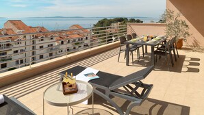 A terrace with a table set for two, a lounge chair, and a potted plant. - Sun Spalato Penthouse (Split)