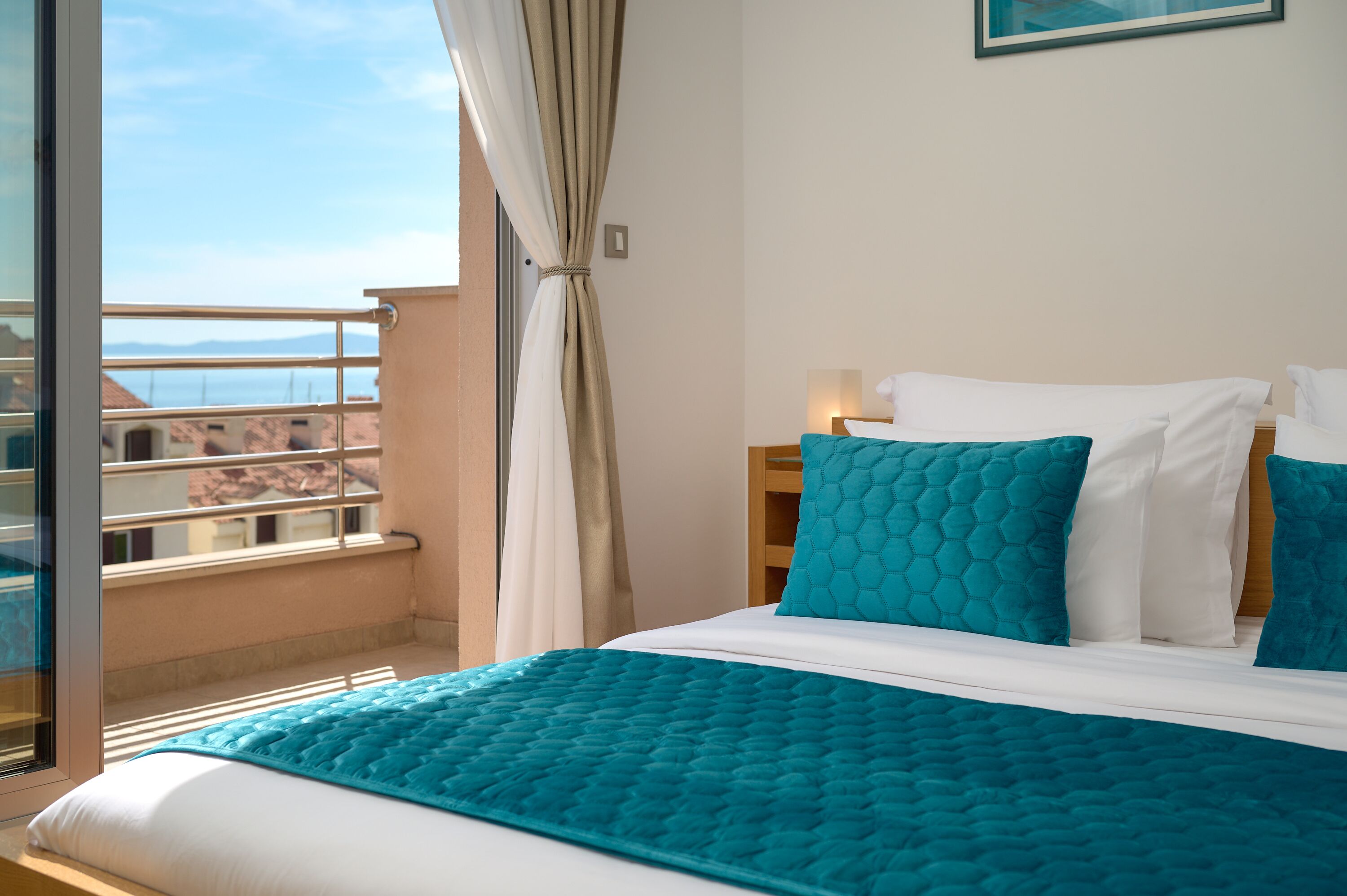 A hotel room with a bed, a nightstand, and a view of the sea.