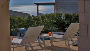 Un espace aménagé au bord de la piscine, comprenant deux chaises longues, une petite table et un élément décoratif aquatique.