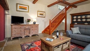 Un salon avec un escalier en bois, une télévision, un canapé et une table basse.