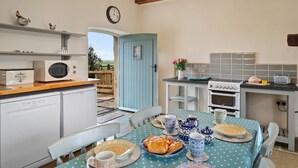 Une cuisine équipée d’une table à manger pour deux personnes, d’un four à micro-ondes, d’un grille-pain et d’une horloge murale.