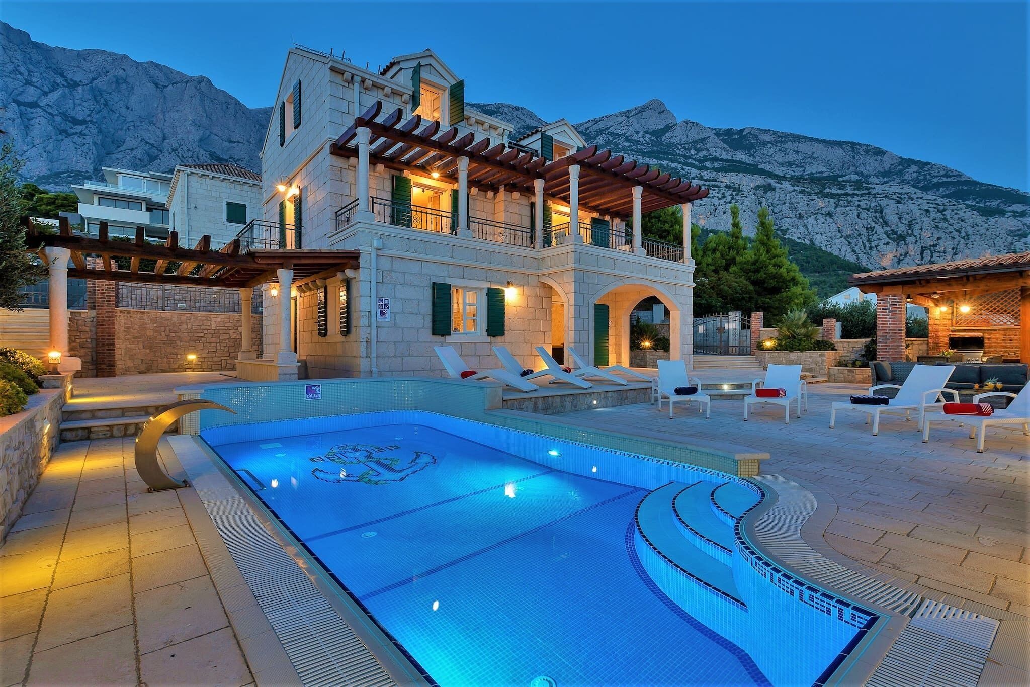 A poolside area with lounge chairs, a swimming pool, and a building with a balcony.