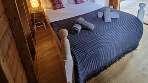 Ein Bett mit Baldachin, Holzboden und ein kleiner Tisch mit Lampe.