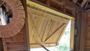 Ein Holzhäuschen im Inneren mit einem Fenster, Holzwänden und einem Spiegel.