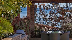 Une terrasse extérieure avec un mur en briques, une table avec des chaises et un luminaire suspendu.
