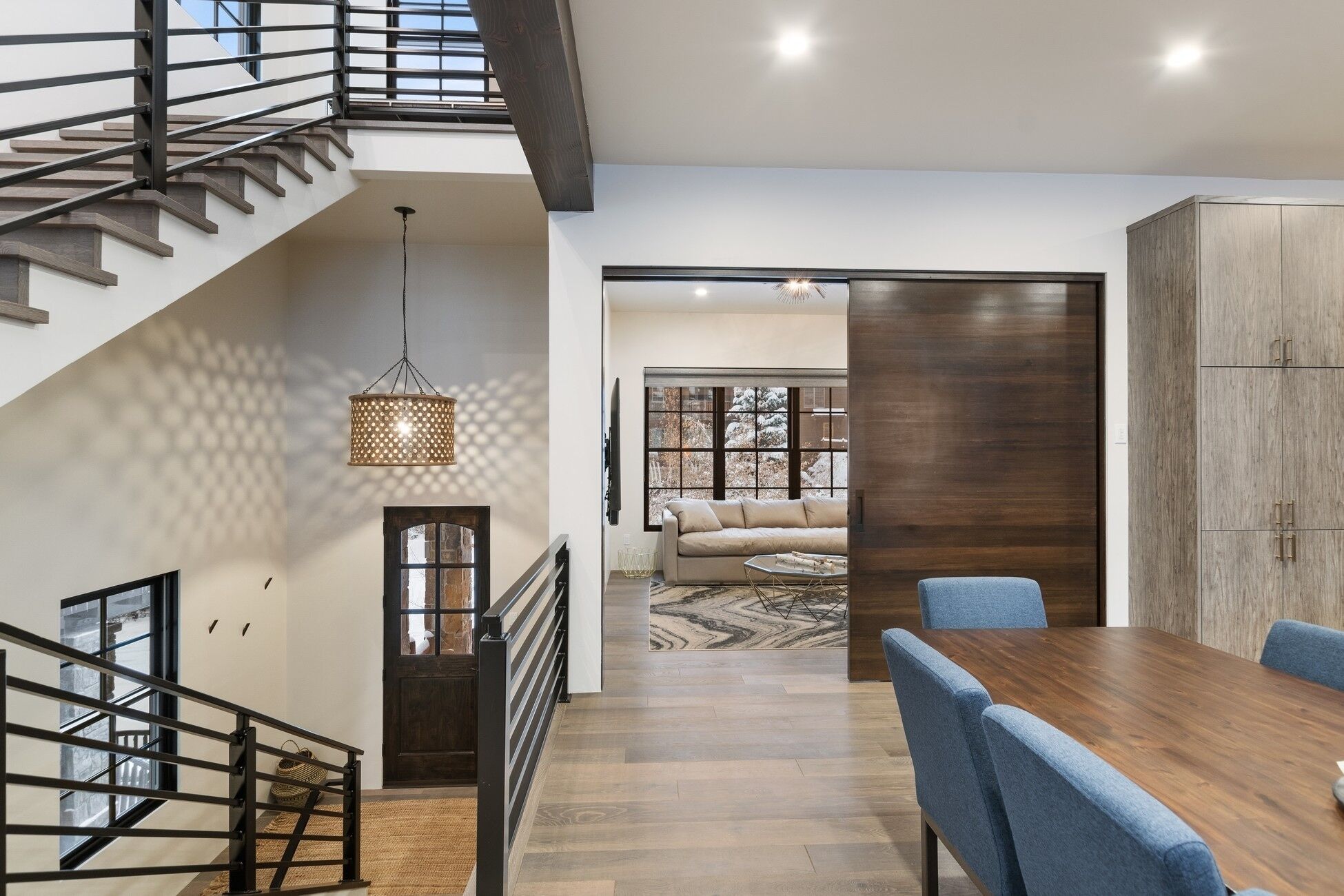 Un intérieur moderne avec un escalier, un coin repas et une vue sur l’extérieur.