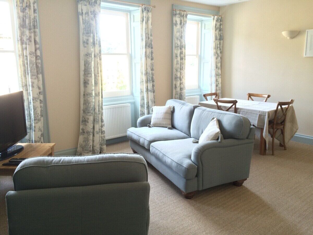 A living room with a sofa, a television, and a dining table with chairs.