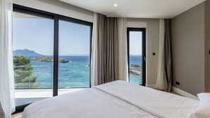 Un dormitorio con una cama grande, vista al mar y una montaña en la distancia.