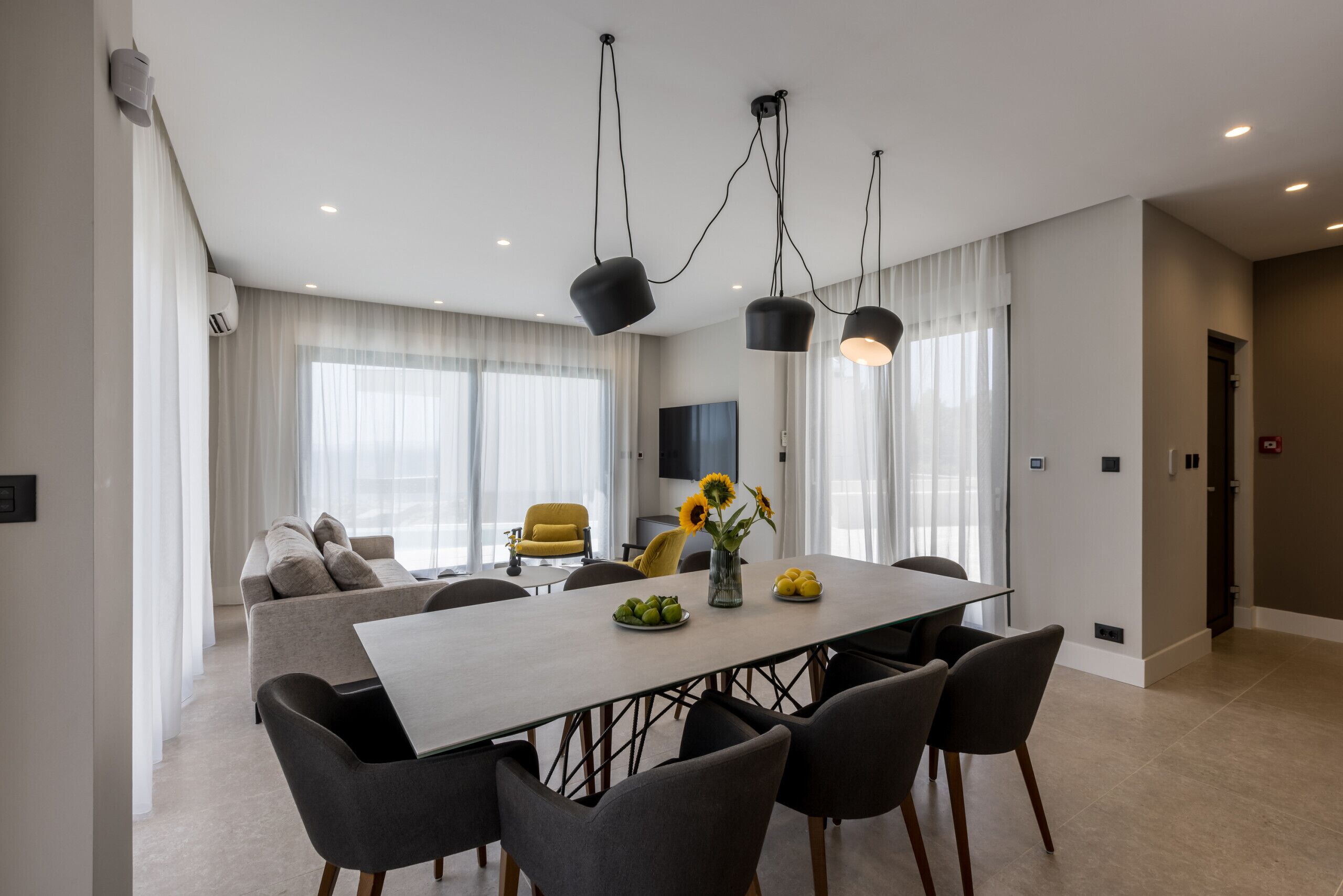 Un comedor moderno con una mesa grande, varias sillas e iluminación colgante.