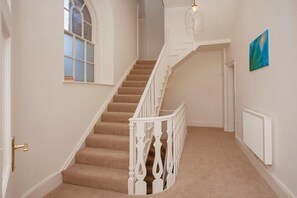 A staircase with white balustrades and beige carpeted steps leading to an upper floor.