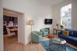 A living room with a sofa, armchairs, a coffee table, a television, and a fireplace.